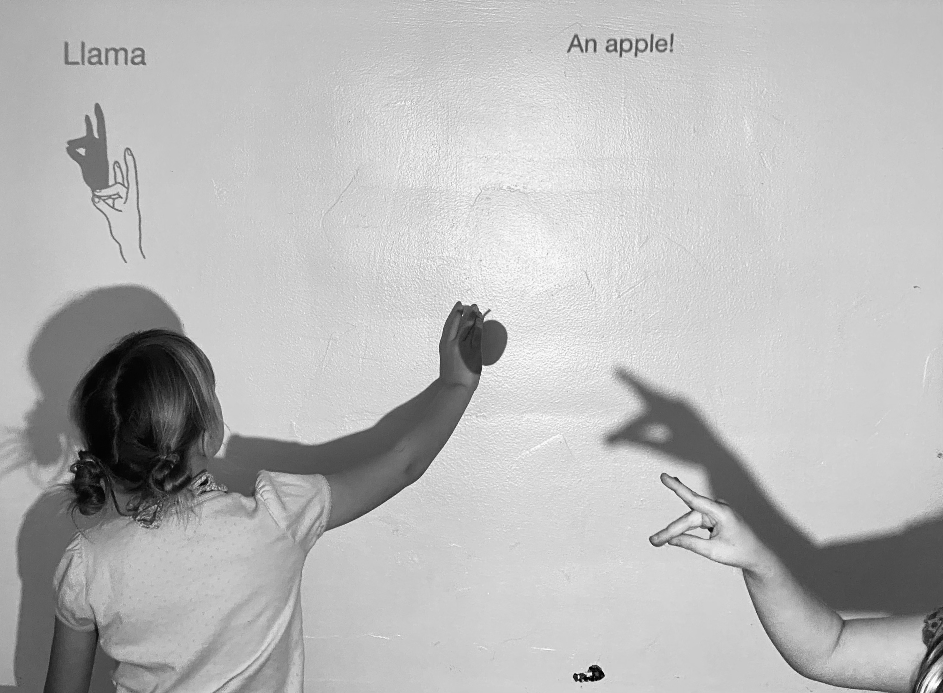 Child interacting with ShadowPlay projection, making a llama shadow puppet